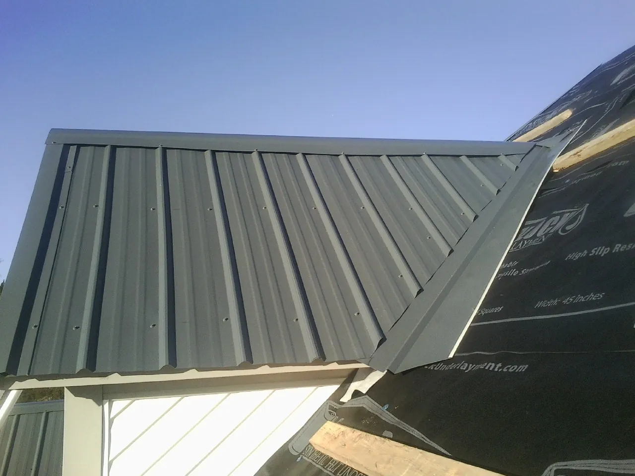 Gray metal roof panels going on over a garage gable in Deanville