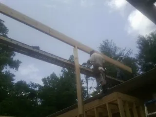 Carpenter setting a ridge beam over a new addition frame — Ice Dam Removal by Roofing Brothers in Deanville