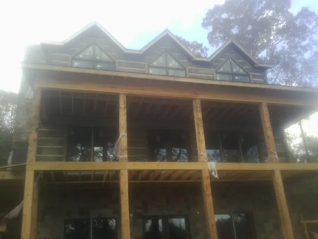 Dormers and porch framing on a large log home under construction — Roof Coating work by our crew in Deanville