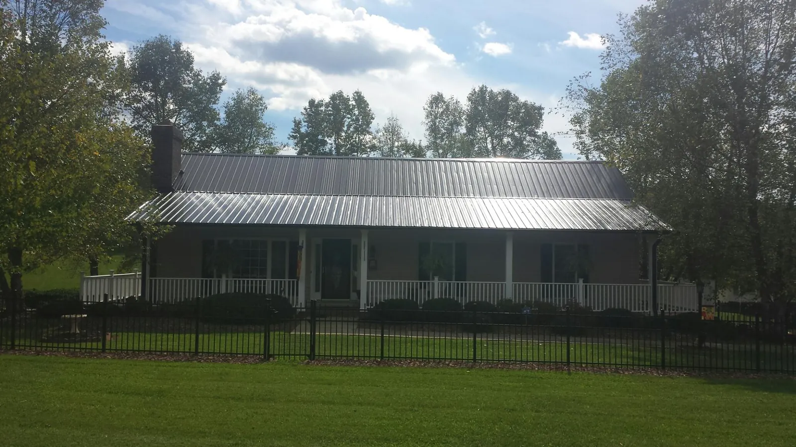 Gray metal roof on a brick ranch with a full width front porch — Gutter Guard Installation work by our crew in Deanville