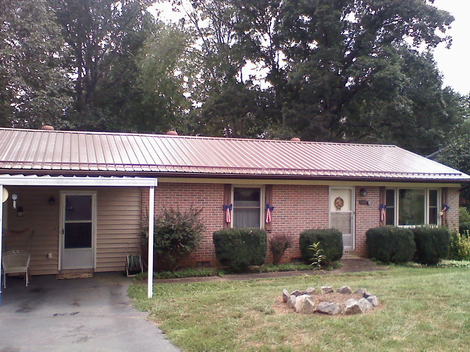 Bronze metal roof and carport on a brick ranch home — Roof Repair work by our crew in Deanville