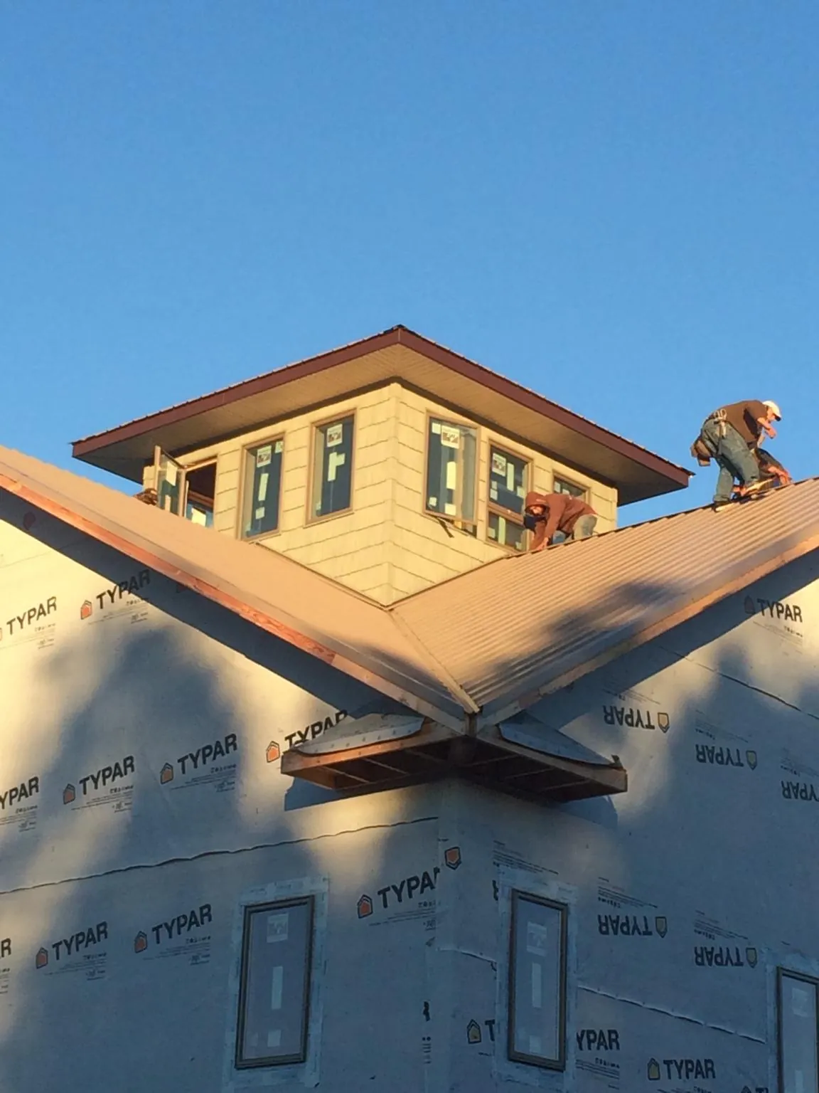 Roofers working around a rooftop cupola on a new metal roof at sunset — Roof Waterproofing in Deanville by Roofing Brothers
